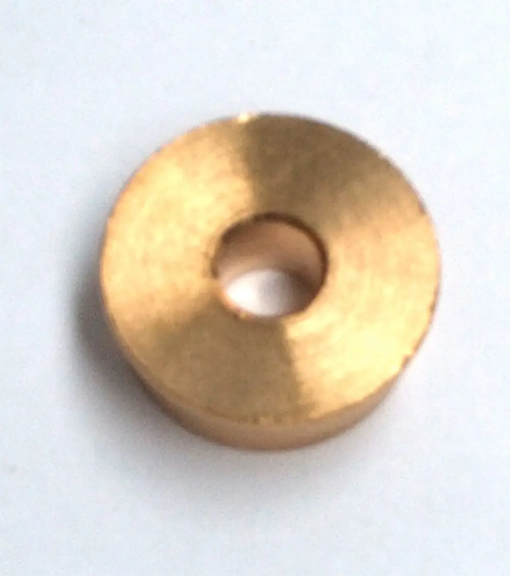 Runde, flache Metallplatte mit zentralem Loch. Sie scheint aus Messing oder einem ähnlichen Material zu bestehen. Möglicherweise eine Bauteilkombination für Daikin-Geräte.